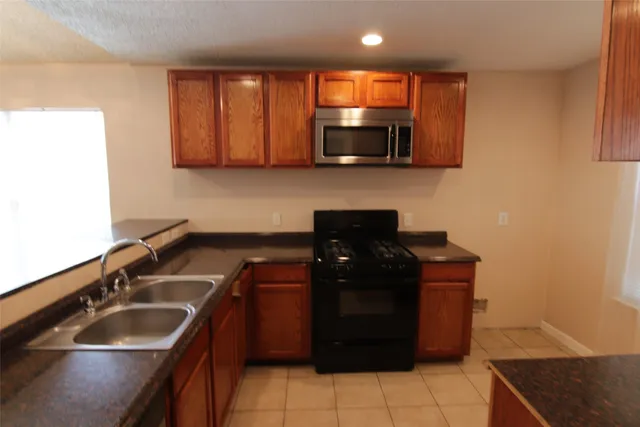 a kitchen with a sink and a stove top oven with wooden floor