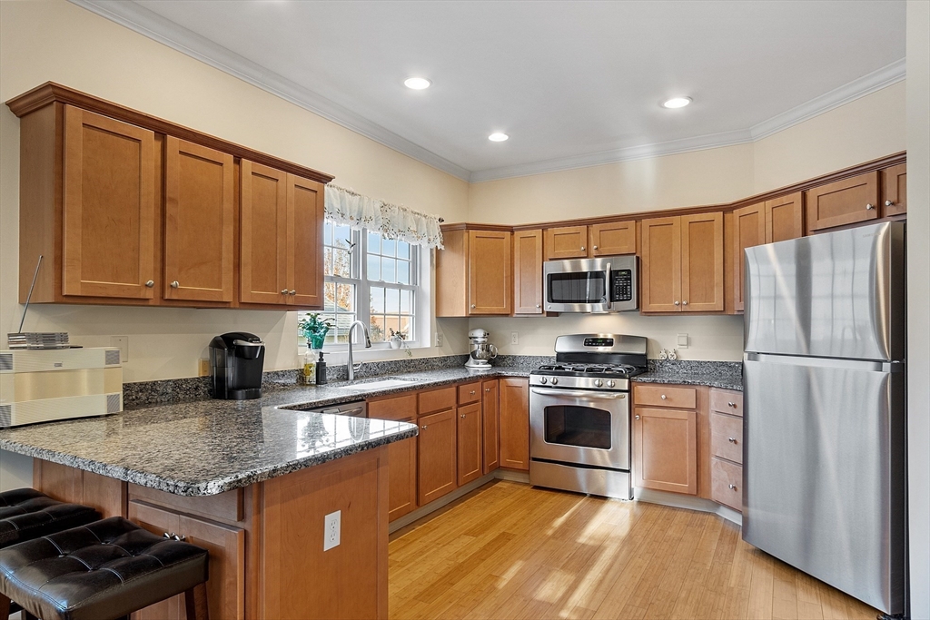 33 Summerfield Drive, Unit 33 Uxbridge, MA 01569 - Photo 16 of 21 a kitchen with stainless steel appliances granite countertop a stove a sink dishwasher a refrigerator and a microwave oven with wooden floor