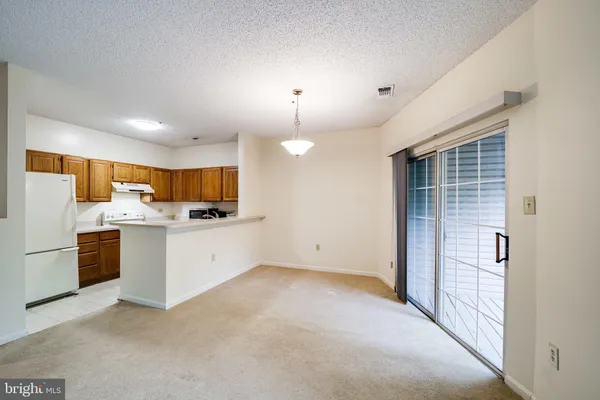a view of a kitchen with refrigerator and white cabinets