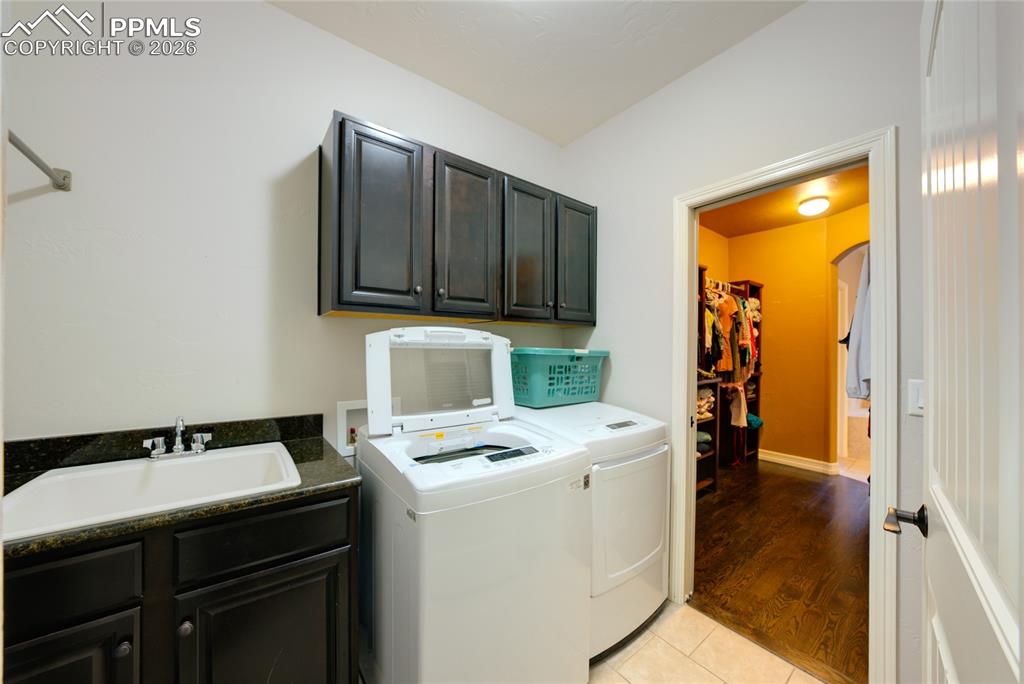 1112 Spectrum Loop Colorado Springs, CO 80921 - Photo 14 of 50 Laundry room with cabinet space, light tile patterned floors, washer and clothes dryer, and arched walkways