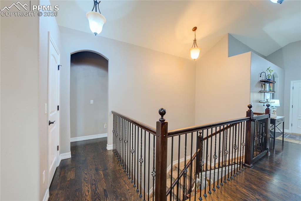 1112 Spectrum Loop Colorado Springs, CO 80921 - Photo 15 of 50 Hall with an upstairs landing, arched walkways, dark wood-style floors, and vaulted ceiling