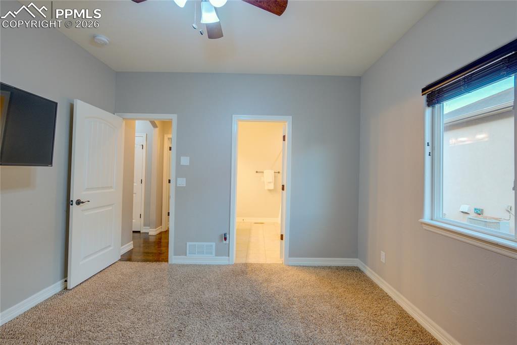 1112 Spectrum Loop Colorado Springs, CO 80921 - Photo 21 of 50 Unfurnished bedroom with carpet flooring, a ceiling fan, and ensuite bathroom