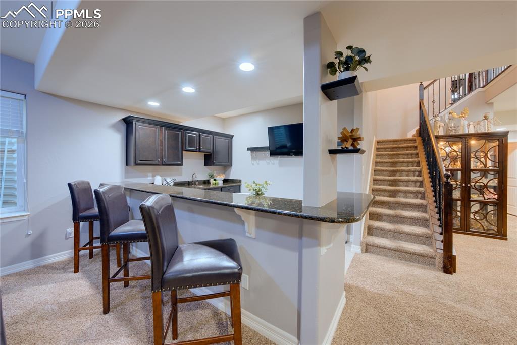 1112 Spectrum Loop Colorado Springs, CO 80921 - Photo 27 of 50 Kitchen with light colored carpet, a kitchen breakfast bar, a peninsula, and recessed lighting