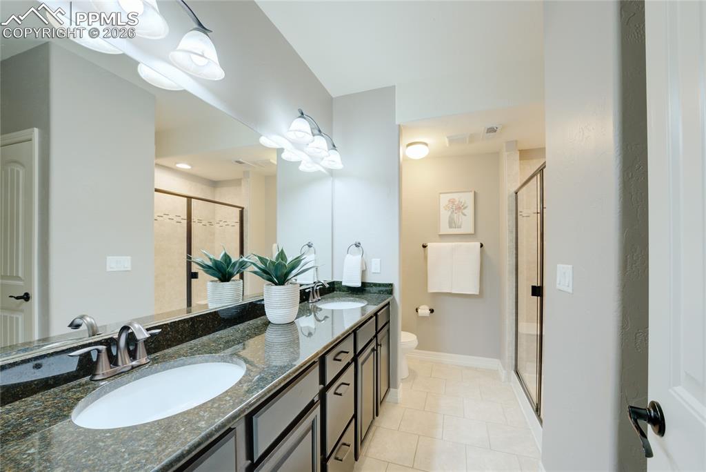 1112 Spectrum Loop Colorado Springs, CO 80921 - Photo 33 of 50 Full bath with a stall shower, double vanity, and light tile patterned floors