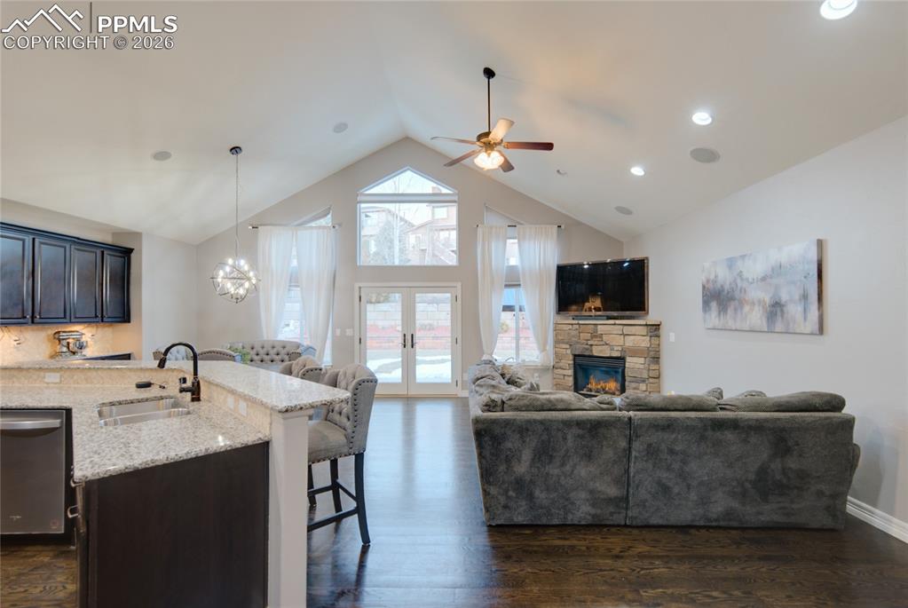 1112 Spectrum Loop Colorado Springs, CO 80921 - Photo 5 of 50 Living room featuring dark wood finished floors, a stone fireplace, a chandelier, high vaulted ceiling, and french doors