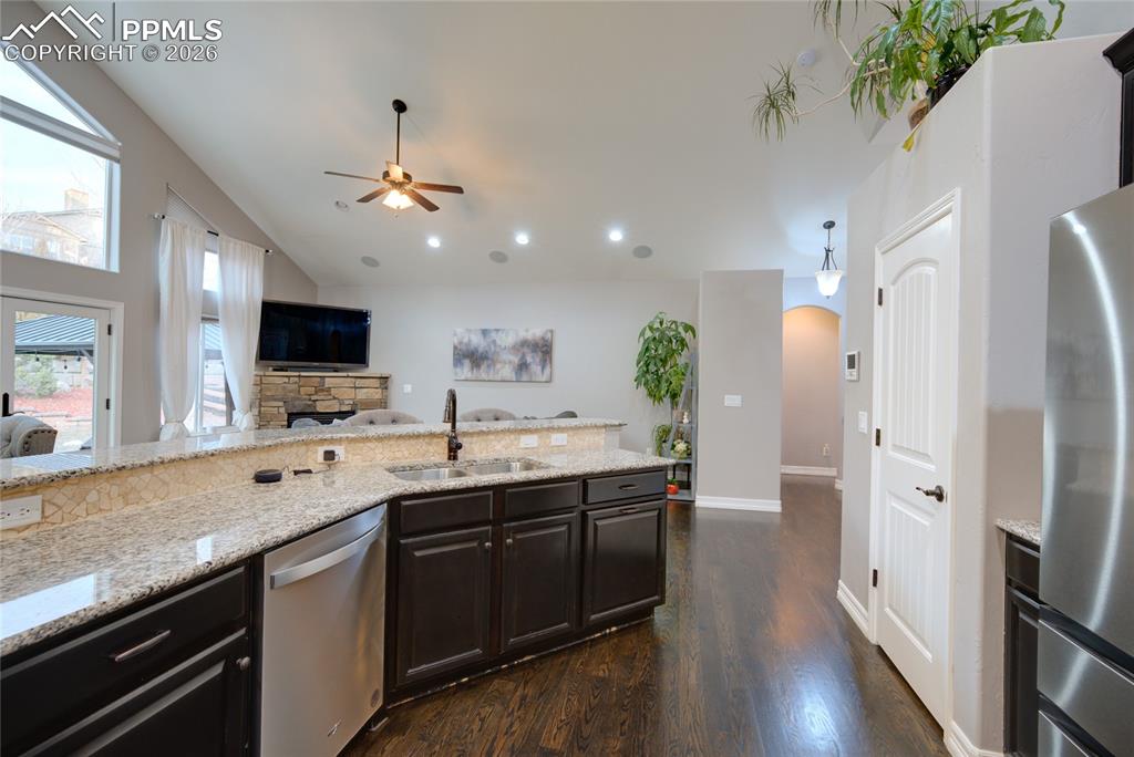 1112 Spectrum Loop Colorado Springs, CO 80921 - Photo 9 of 50 Kitchen featuring arched walkways, stainless steel appliances, lofted ceiling, open floor plan, and light stone counters