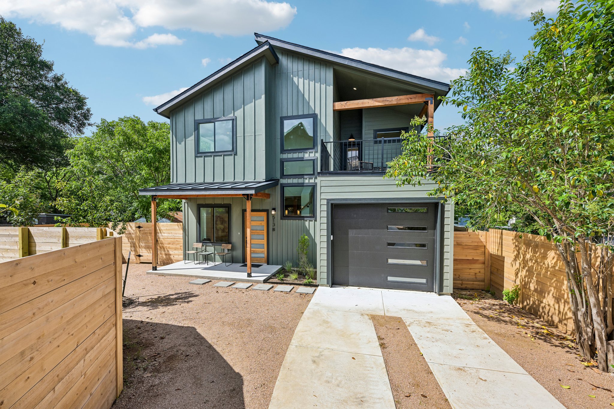 513 West Odell Street, Unit B Austin, TX 78752 - Photo 2 of 38 Modern green-sided home with a balcony, garage, and charming front porch.