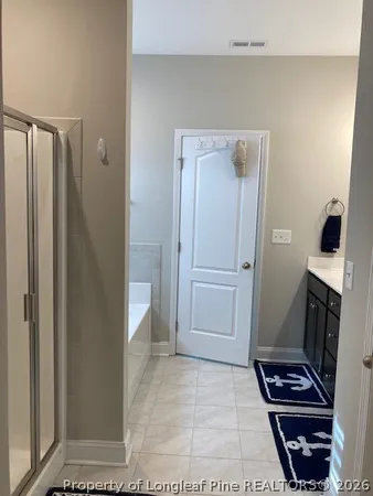 a view of a hallway with wooden floor and a bathroom