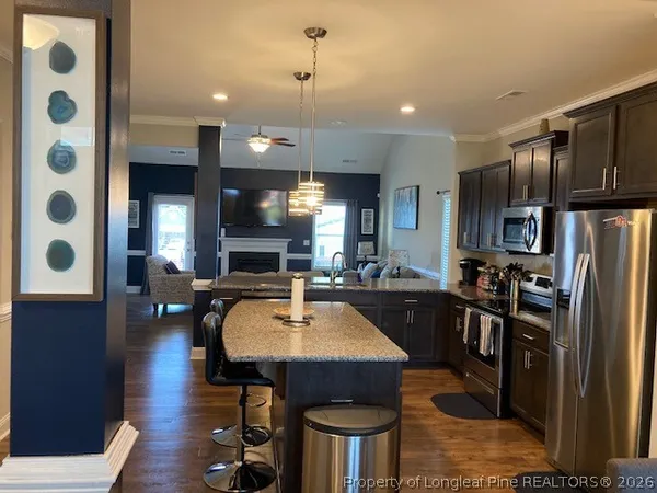 a kitchen with stainless steel appliances granite countertop a refrigerator a sink dishwasher a stove and a dining table with wooden floor