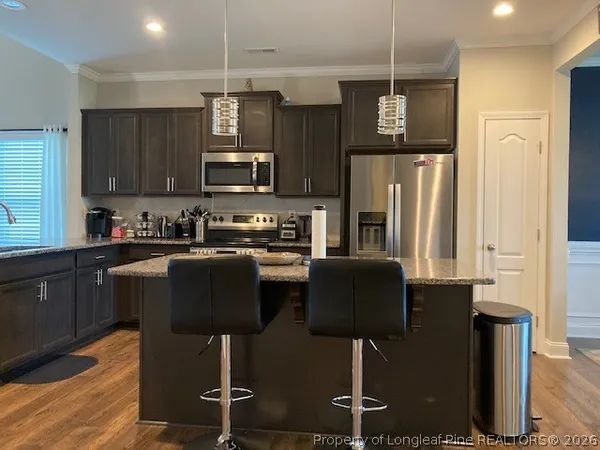 a kitchen with stainless steel appliances granite countertop a refrigerator a stove a sink dishwasher and a microwave oven with wooden floor