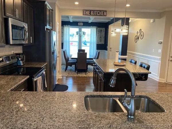 a kitchen with kitchen island granite countertop a sink a stove and a refrigerator