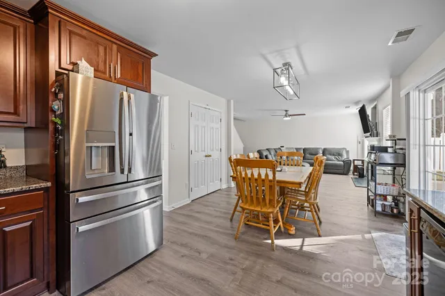 a kitchen with stainless steel appliances kitchen island granite countertop a refrigerator a stove a microwave oven with a dining table and chairs with wooden floor