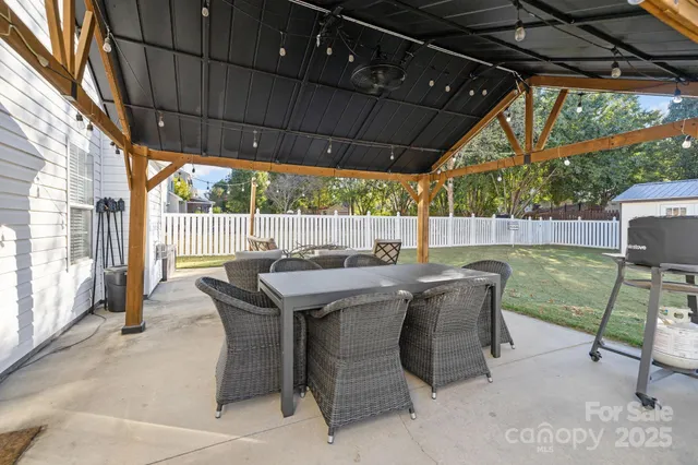 a view of a patio with table and chairs under an umbrella with a small yard