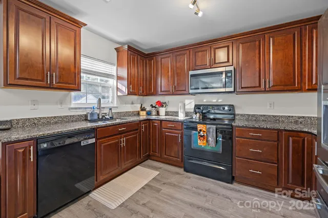 a kitchen with stainless steel appliances granite countertop wooden cabinets a stove top oven a sink and dishwasher