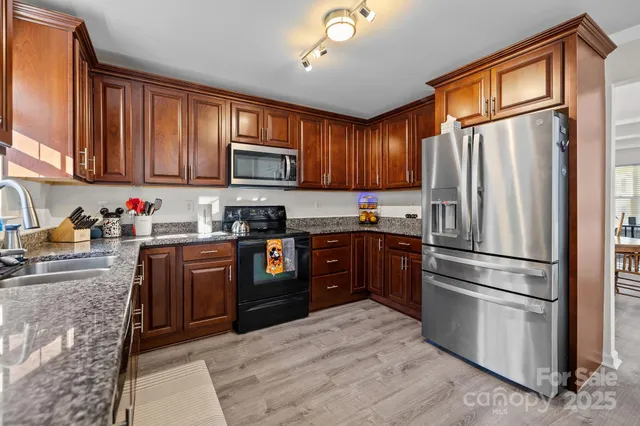a kitchen with granite countertop wooden cabinets a refrigerator stove top oven and sink