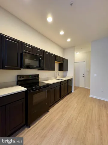 a large kitchen with stainless steel appliances a stove a sink dishwasher a microwave oven with cabinets and wooden floor