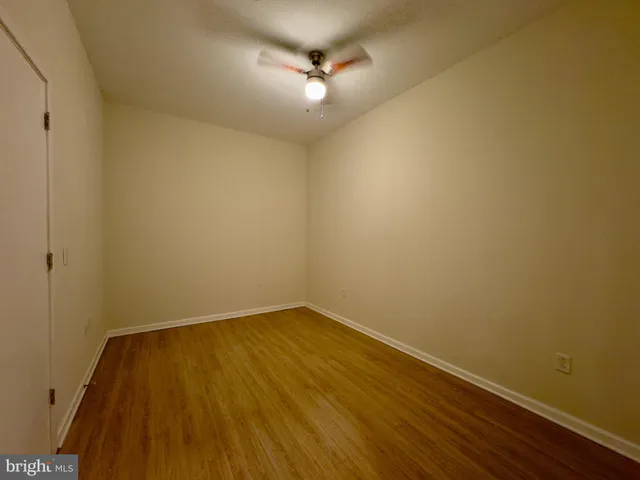 a view of a room with wooden floor and a ceiling fan