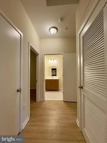 a view of a hallway with wooden floor and a bathroom
