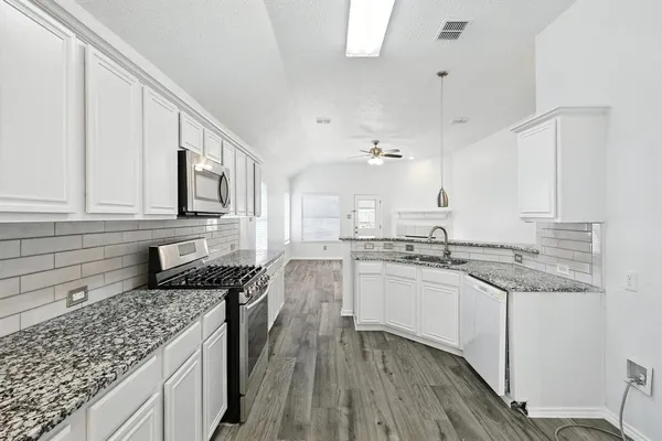 a kitchen with granite countertop cabinets stainless steel appliances a sink and a counter space