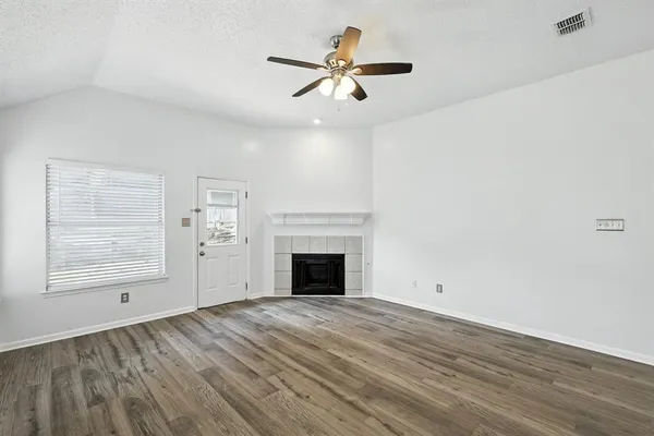 wooden floor fireplace and windows in an empty room