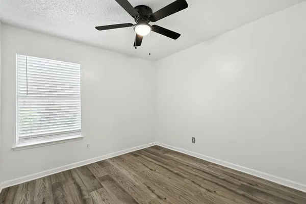 an empty room with a window and a ceiling fan