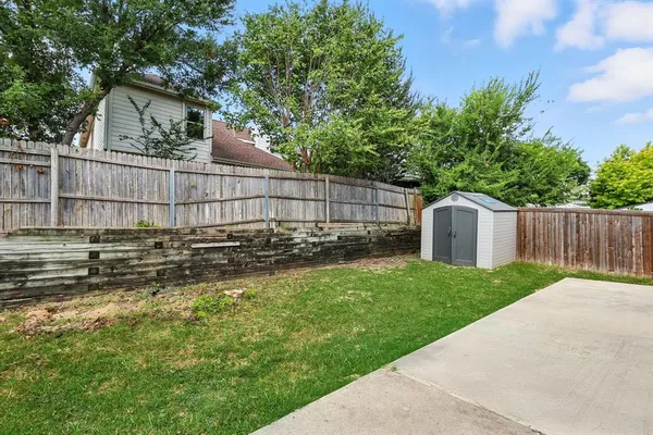 a view of a backyard with a large tree and wooden fence