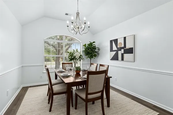 a view of a dining room with furniture a chandelier and wooden floor
