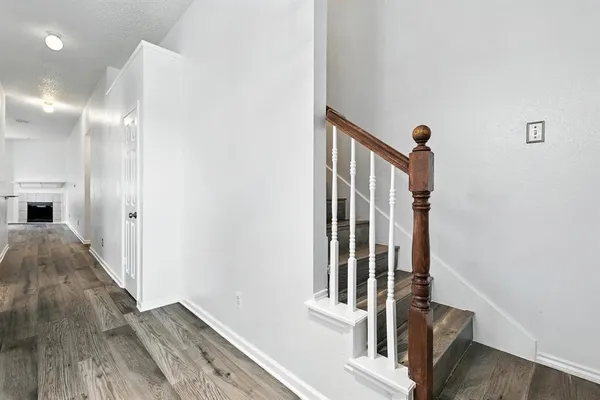 a view of a hallway with wooden floor and staircase