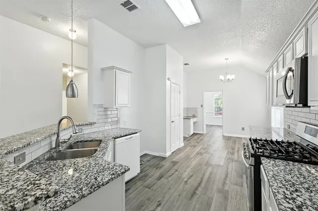 a kitchen with granite countertop a sink stove and refrigerator