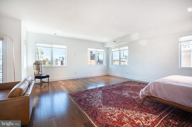 a spacious bedroom with a bed and wooden floor