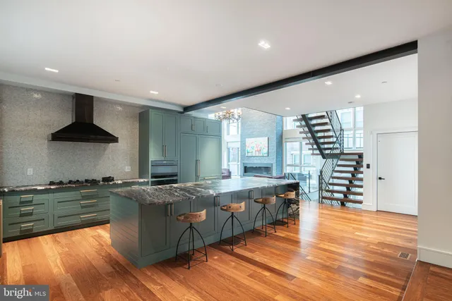 a large kitchen with stainless steel appliances granite countertop a lot of counter space and wooden floors