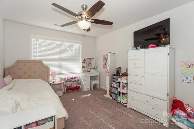 a bedroom with a bed a flat screen tv and a window