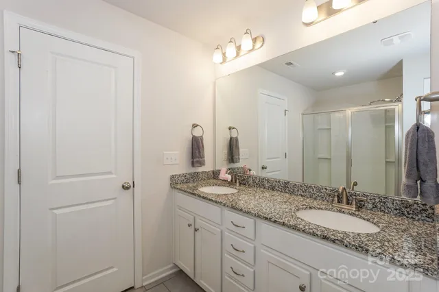 a bathroom with a granite countertop double vanity sink and a mirror