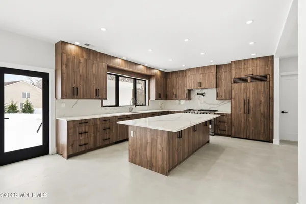 a large kitchen with stainless steel appliances a sink a stove and a refrigerator