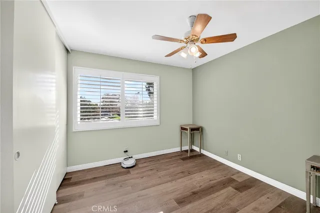 an empty room with wooden floor fan and windows