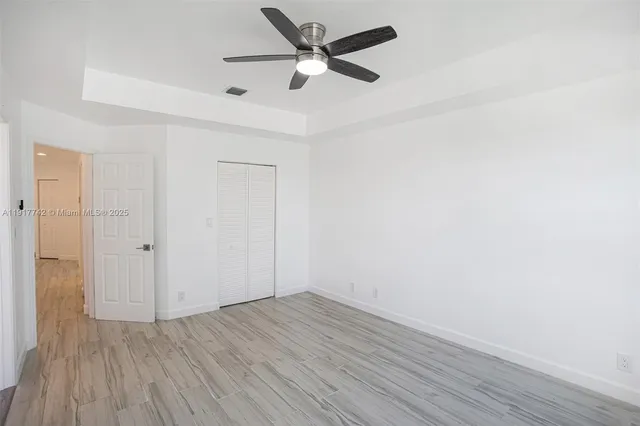 a view of a hallway with wooden floor and a bathroom