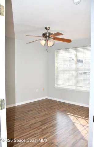 a view of empty room with wooden floor and fan