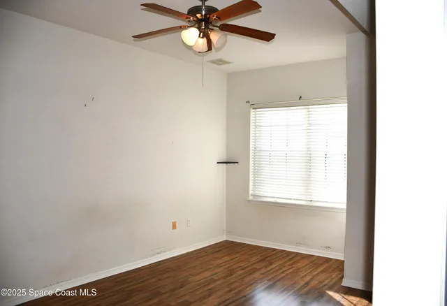 a view of an empty room with a window and wooden floor