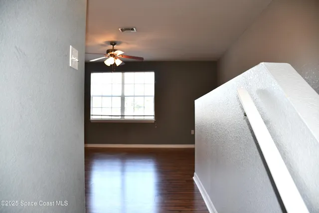 a view of empty room with wooden floor and fan