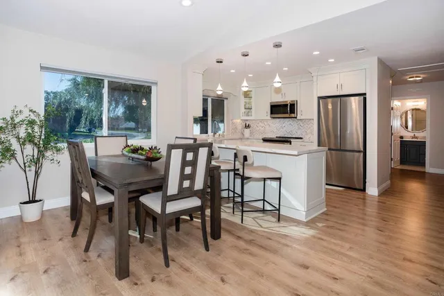 a kitchen with stainless steel appliances kitchen island granite countertop a table chairs and a refrigerator