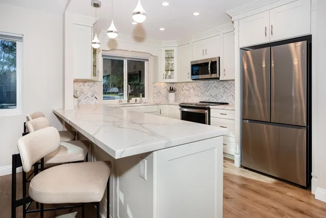 a kitchen with a table stainless steel appliances a refrigerator and microwave