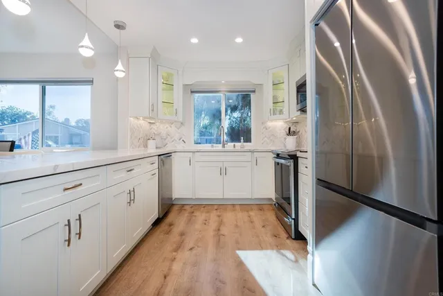a large white kitchen with a large window a refrigerator and a sink