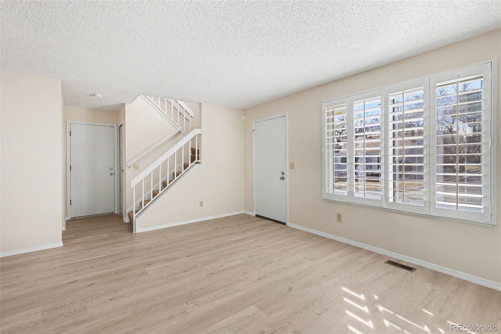15922 East Rice Place, Unit B Aurora, CO 80015 - Photo 3 of 30 a view of an empty room with wooden floor and a window