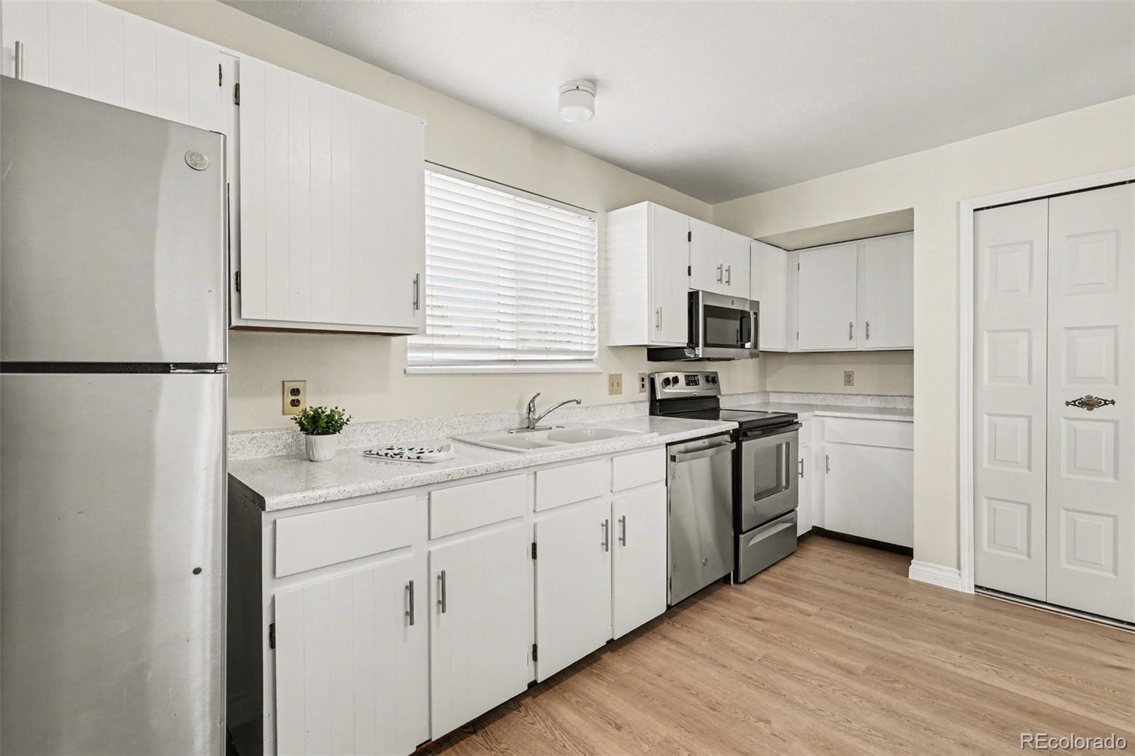 15922 East Rice Place, Unit B Aurora, CO 80015 - Photo 9 of 30 a kitchen with granite countertop white cabinets and white appliances