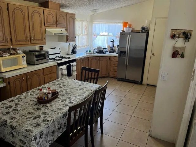 a kitchen with stainless steel appliances a dining table chairs refrigerator and cabinets