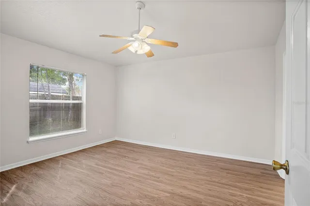 a view of a hallway with wooden floor and a chandelier fan