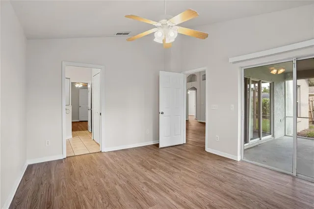 an empty room with wooden floor and ceiling fan