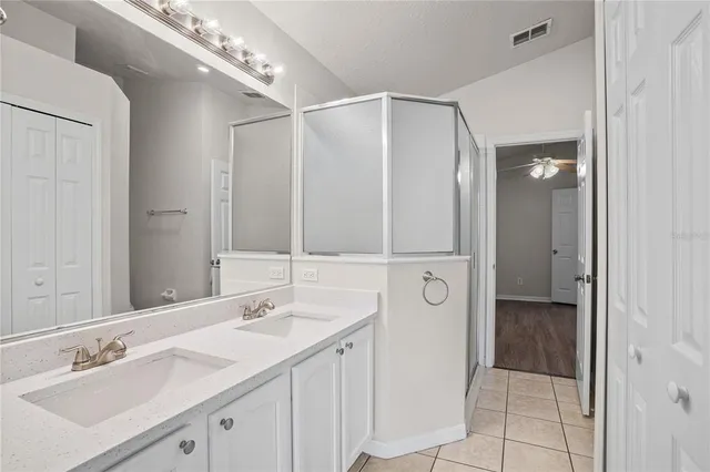 an empty room with wooden floor chandelier fan and windows