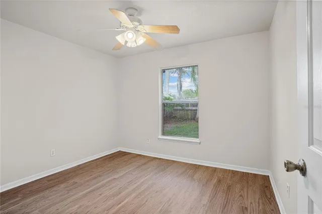 an empty room with wooden floor closet and windows