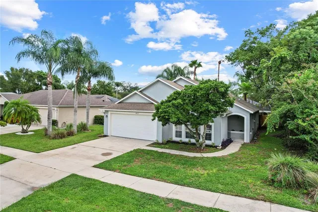 a view of a house with a yard potted plants and a large tree